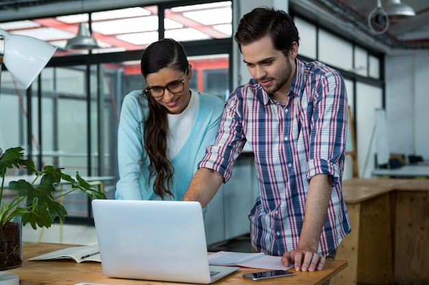 Business executives discussing over laptop