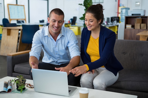 Business executives discussing over laptop