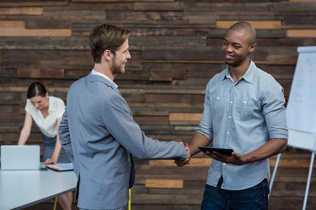 Business executives shaking hands in office