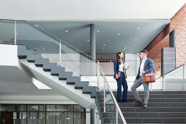 Business executives standing on stairs and discussing project details and gossips