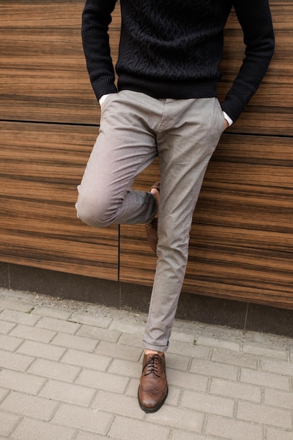 business fashion casual clothing style. relaxed unrecognizable man leaning on the wood texture wall outdoors