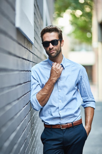 Business fashion confidence and portrait of man with glasses professional clothes and leaning on city wall Designer outfit luxury apparel and businessman with cool attitude style and formal wear