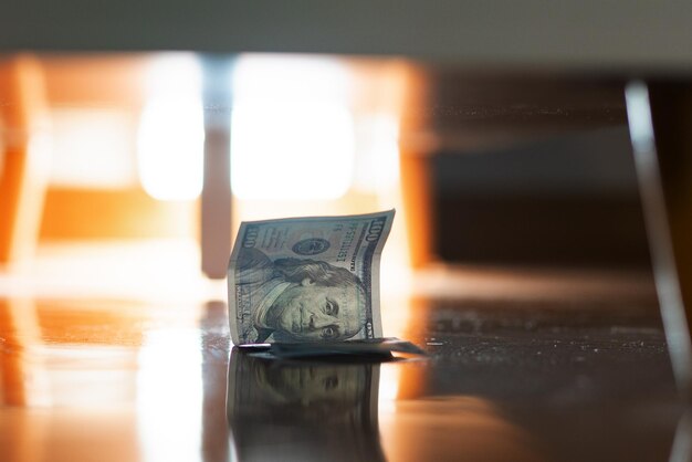 失われたドル紙幣が家具の下のパルケットの床に横たわっている 失価償却とインフレの概念