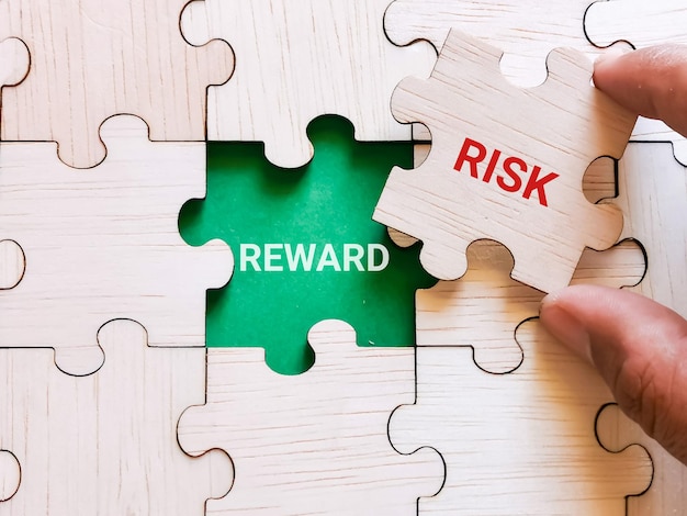 Photo business and finance concept. phrase risk reward written on jigsaw puzzle with hand.