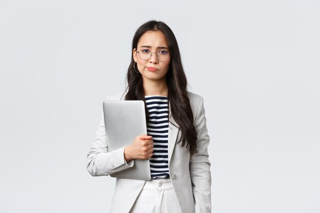 Photo business, finance and employment, female successful entrepreneurs concept. sad and doubtful businesswoman having hesitations about meeting, smirk displeased, holding laptop