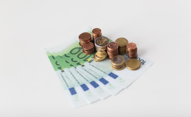 business, finance, investment, saving and cash concept - close up of euro paper money and coins on table