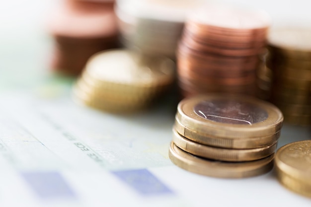 business, finance, investment, saving and cash concept - close up of euro paper money and coins on table