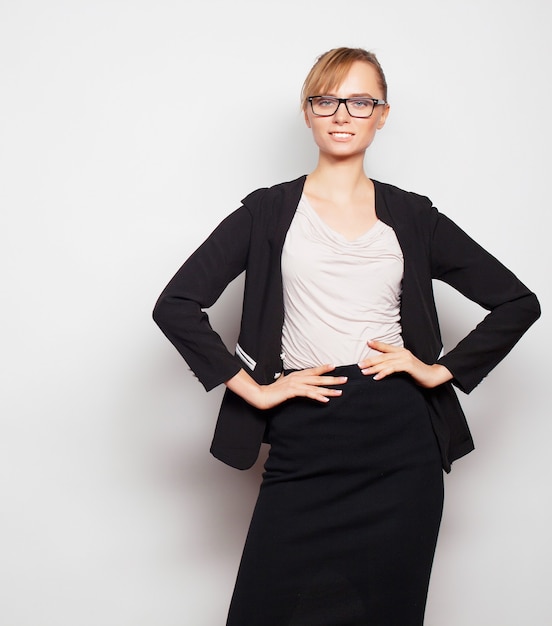 Concetto di affari, finanza e persone: giovane donna d'affari con gli occhiali. su sfondo grigio.