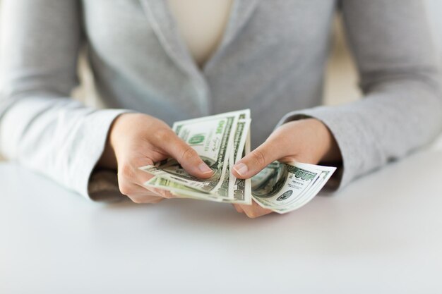 business, finance, saving, banking and people concept - close up of woman hands counting us dollar money