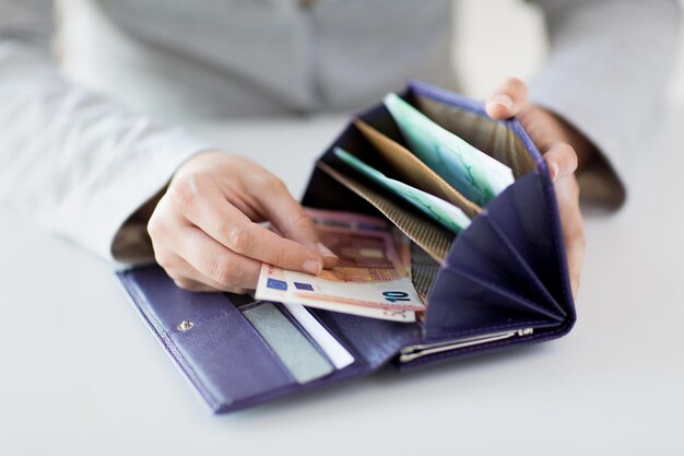 business, finance, saving, banking and people concept - close up of woman hands with wallet and euro money