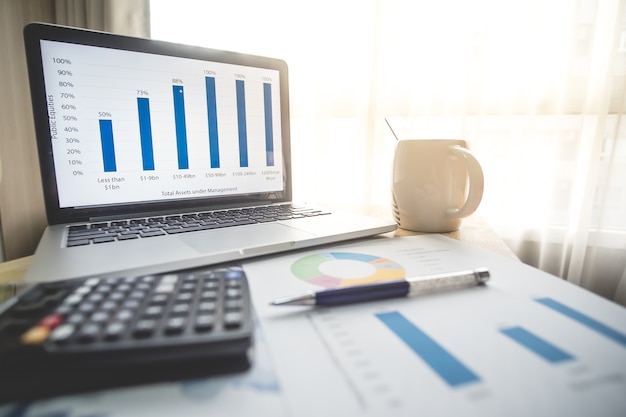 Фото Бизнес-концепция финансов ноутбук, ручка, кофе, график для финансов, бизнес на столе