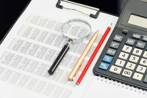 Business financial documents, office calculator and pen on the table. Numbers and graphs