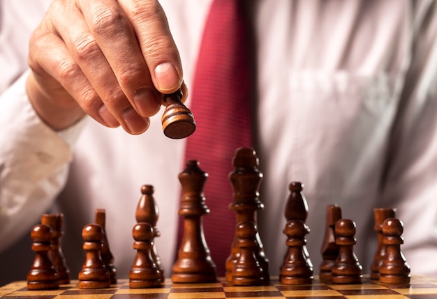 Business financial strategy concept. Businessman making decision and moving chess piece over other chess figures.