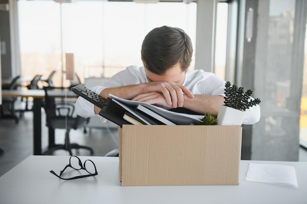 Business firing and job loss concept fired male office worker with box of his personal stuff