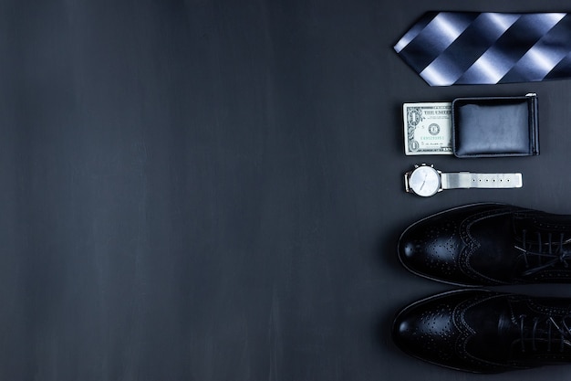 コピースペースとビジネスフラットレイ背景。男性の靴、腕時計の財布、ベルト、携帯電話、黒の背景にネクタイ。