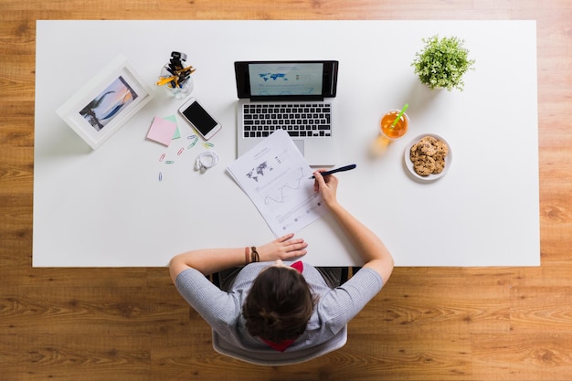 концепция бизнеса, фрилансера и людей - женщина с ноутбуком и бумагами за офисным столом