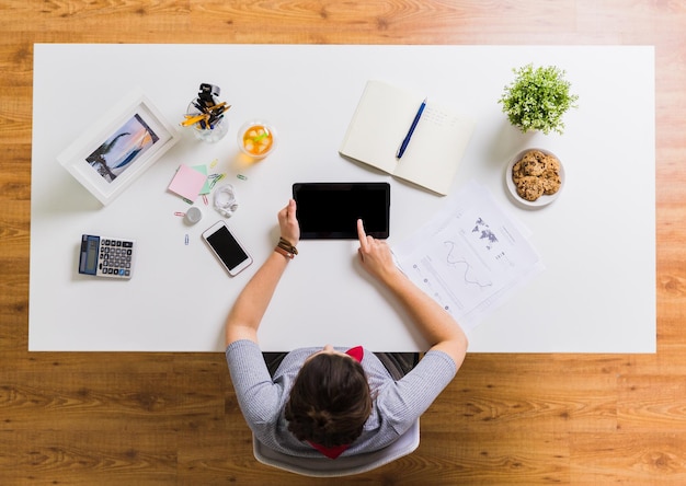 business, freelance and technology concept - woman with tablet pc computer and notebook at office table