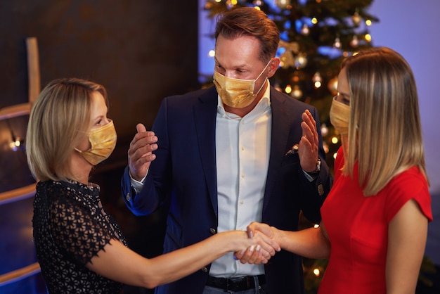 Business friends celebrating christmas party wearing masks. High quality photo