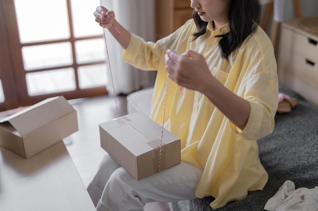 写真 アジアの女性がパッケージ配達ボックスを準備しています オンラインショッピングのための配送 若いスタートアップ 小規模事業主の自宅でのオンライン注文