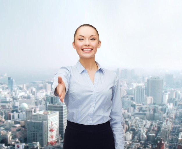 business, gesture and education concept - friendly young smiling businesswoman with opened hand ready for handshake