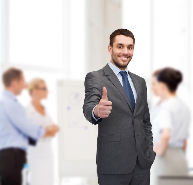 business, gesture and office concept - handsome buisnessman showing thumbs up in office