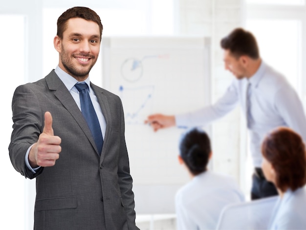 business, gesture and office concept - handsome buisnessman showing thumbs up in office