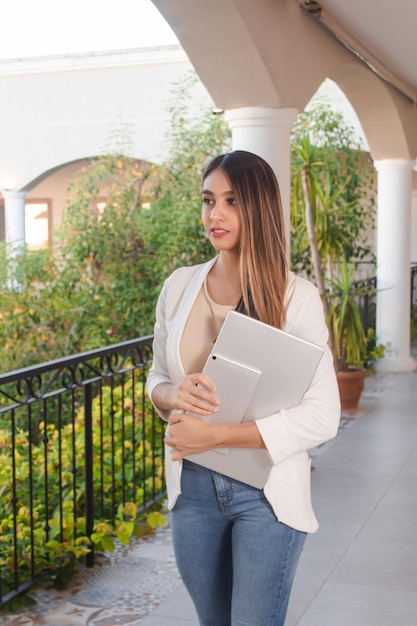 Business girl carrying a laptop with her arms on a hotel balcony Vertical image