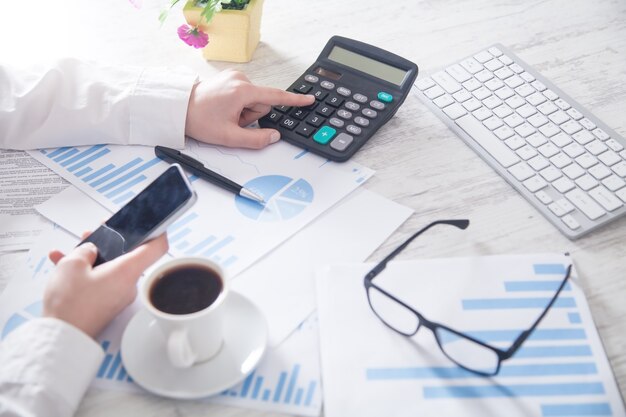 Business girl using calculator. Working in office. Financial graphs and Investment