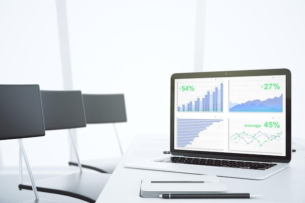 Business graph on laptop screen in modern light conference room