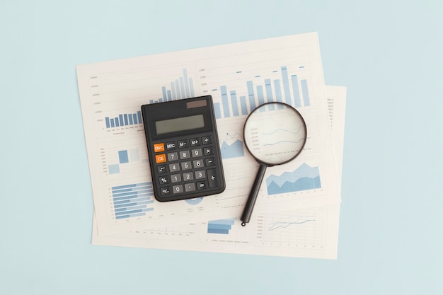 Business graphs charts magnifying glass and calculator on table Financial development