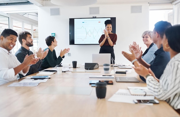 A business group clapping in a boardroom meeting colleagues celebrating success at a presentation