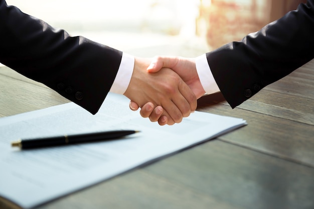 Бизнес-рукопожатие в бумажной работе после успешного подписания контракта