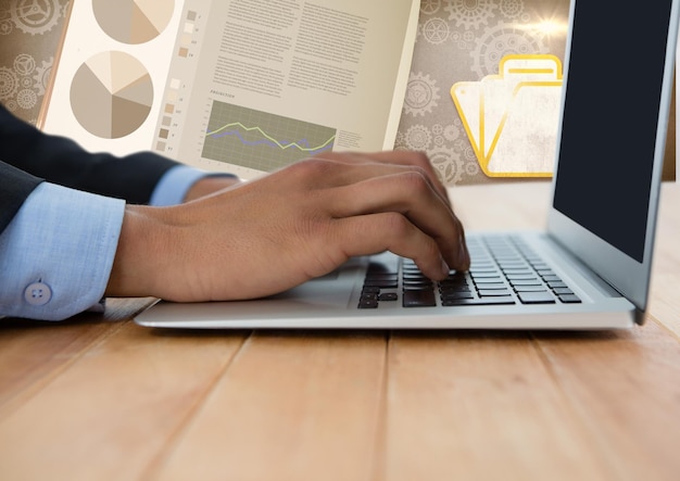 Business hand with laptop at desk with diagrams and charts