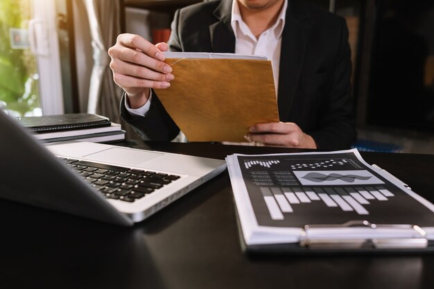 Mano d'affari che lavora con un nuovo computer moderno e scrive sul diagramma della strategia del blocco note come luce del mattino concettuale