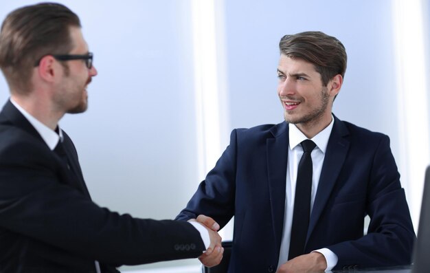 Business hands shaking hands sitting at the Deskphoto with copy space