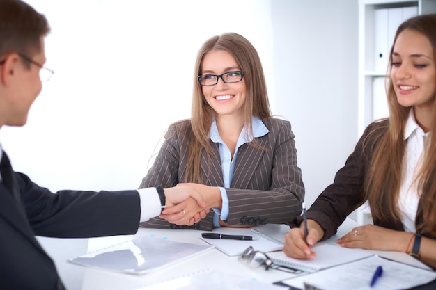 Business handshak  sitting at the desk on office background, copy space area at the left upper corner