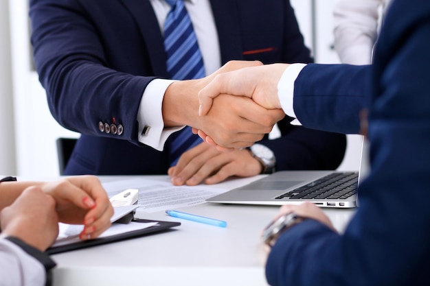 Business handshake at meeting or negotiation in the office. Partners are satisfied because signing contract or financial papers.