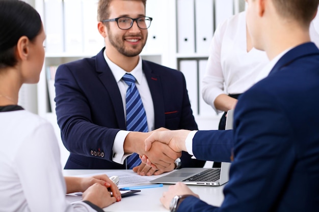 Business handshake at meeting or negotiation in the office. Partners are satisfied because signing contract or financial papers.