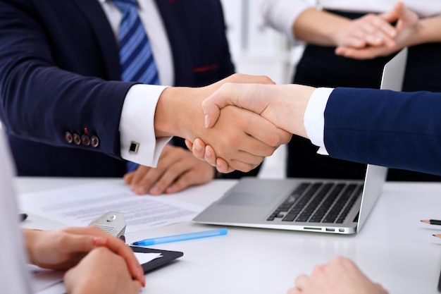 Business handshake at meeting or negotiation in the office. Partners are satisfied because signing contract or financial papers.