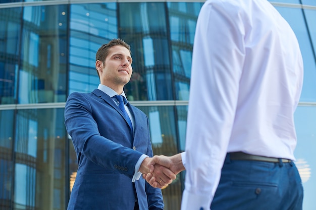 Business handshake outside the business center. Partnership meeting concept. Successful businessmen handshaking after good deal.