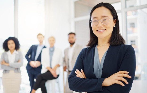 Business happy and portrait of Asian woman in office with confidence pride and motivation with team Leadership diversity and female worker with smile for success company mission and happiness