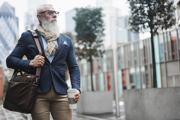 Business hipster senior man permanent zelfverzekerd terwijl het drinken van koffie op winterdag - focus op gezicht