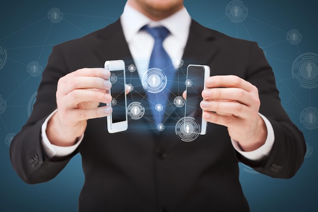 ビジネス、インターネット、技術の概念-空白の黒い画面で2つのスマートフォンを示すビジネスマン