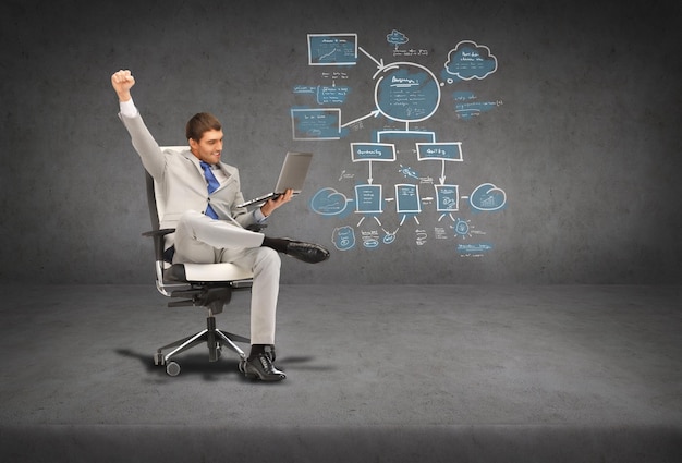 business, internet and technology concept - young businessman sitting in chair with laptop and big plan on the back