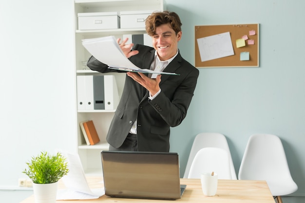 Business, joke, people concept - happy man throwing the paper because he has finished his work