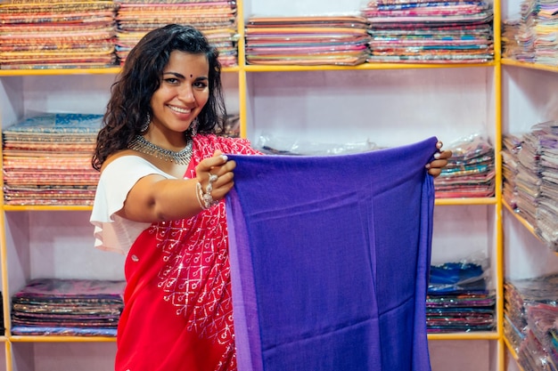 Photo business lady in red traditional sari and jewelery clothes shop owner cashmere yak wool shawlsfemale seller in goa india arambol sale shopdesigner seamstress tailor girl choosing fabric