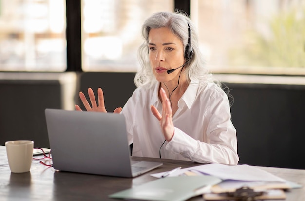 Business lady solving customers issues video calling via laptop indoors