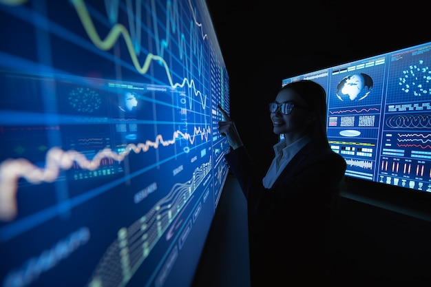 어두운 실험실에서 블루 스크린 근처에 서 있는 비즈니스 여성