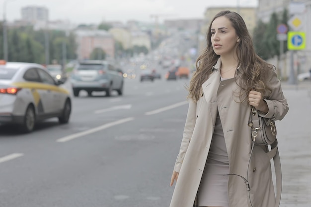 business lady stands road, cars, traffic, urban style, travel in the city, woman and cars