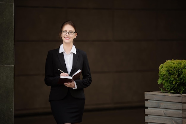 A business lady with glasses makes a note in a notebookManagement concept